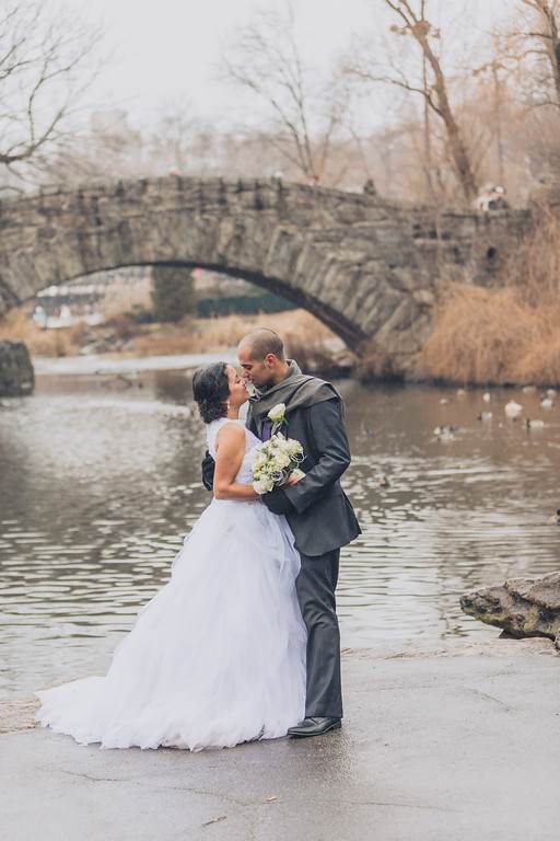 Pareja de recién casados besándose junto al lago en Central Park, Nueva York